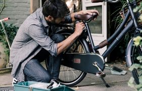 Een man is een fietszadel aan het verstellen