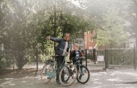Man en kind met fiets in de hand. De man wijst iets aan.