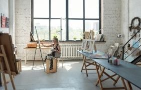 Vrouw zit te schilderen in een grote, lichte ruimte