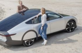 2 vrouwen praten met elkaar, leunend op een auto op zonne-energie