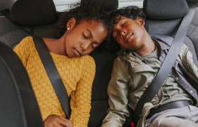 2 kinderen zitten slapend op de achterbank van een auto