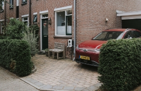 Een auto staat op de oprit geparkeerd, naast een huis